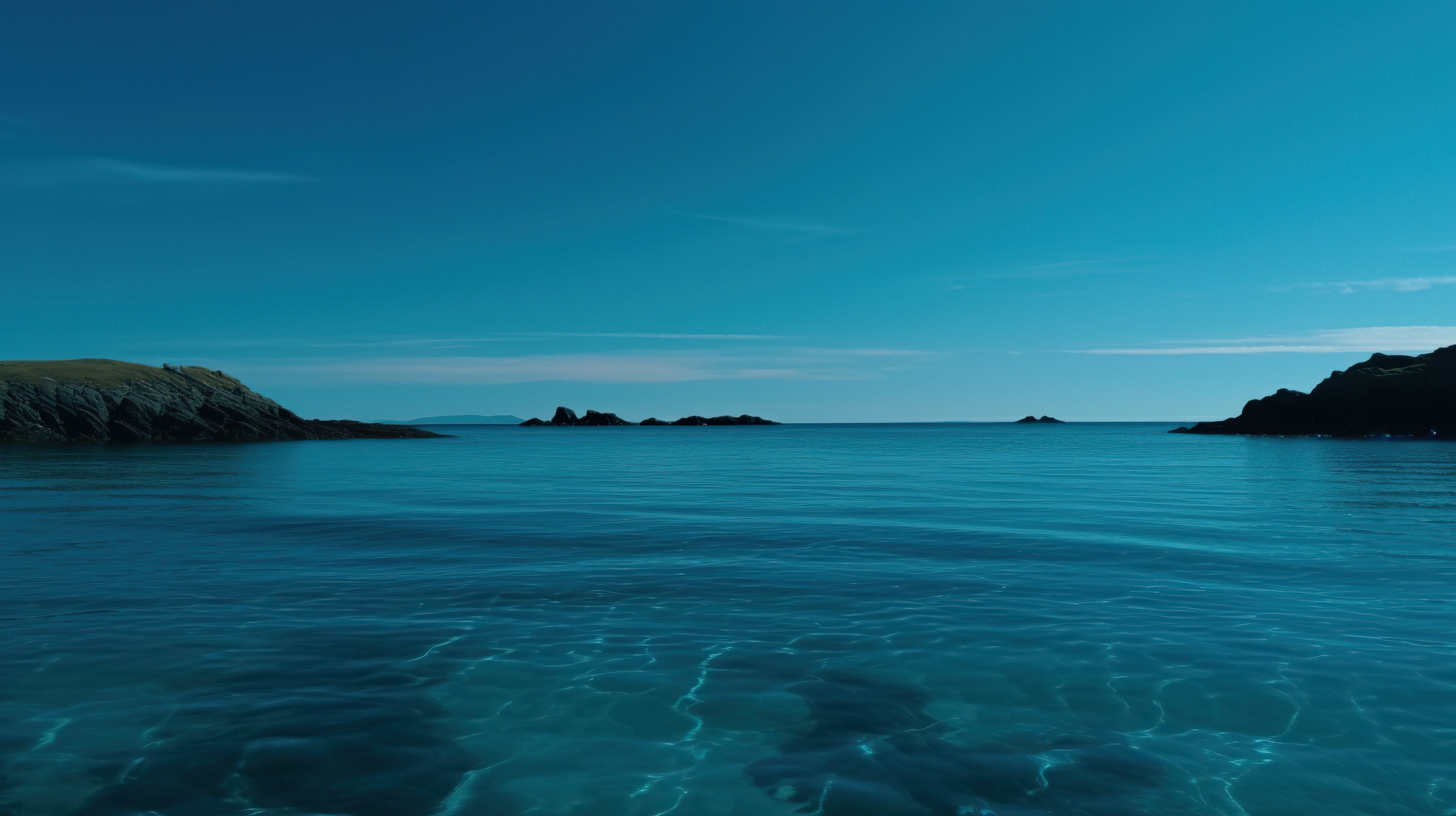 Beautiful blue sky and a beach with clear blue water and rocks on the shore