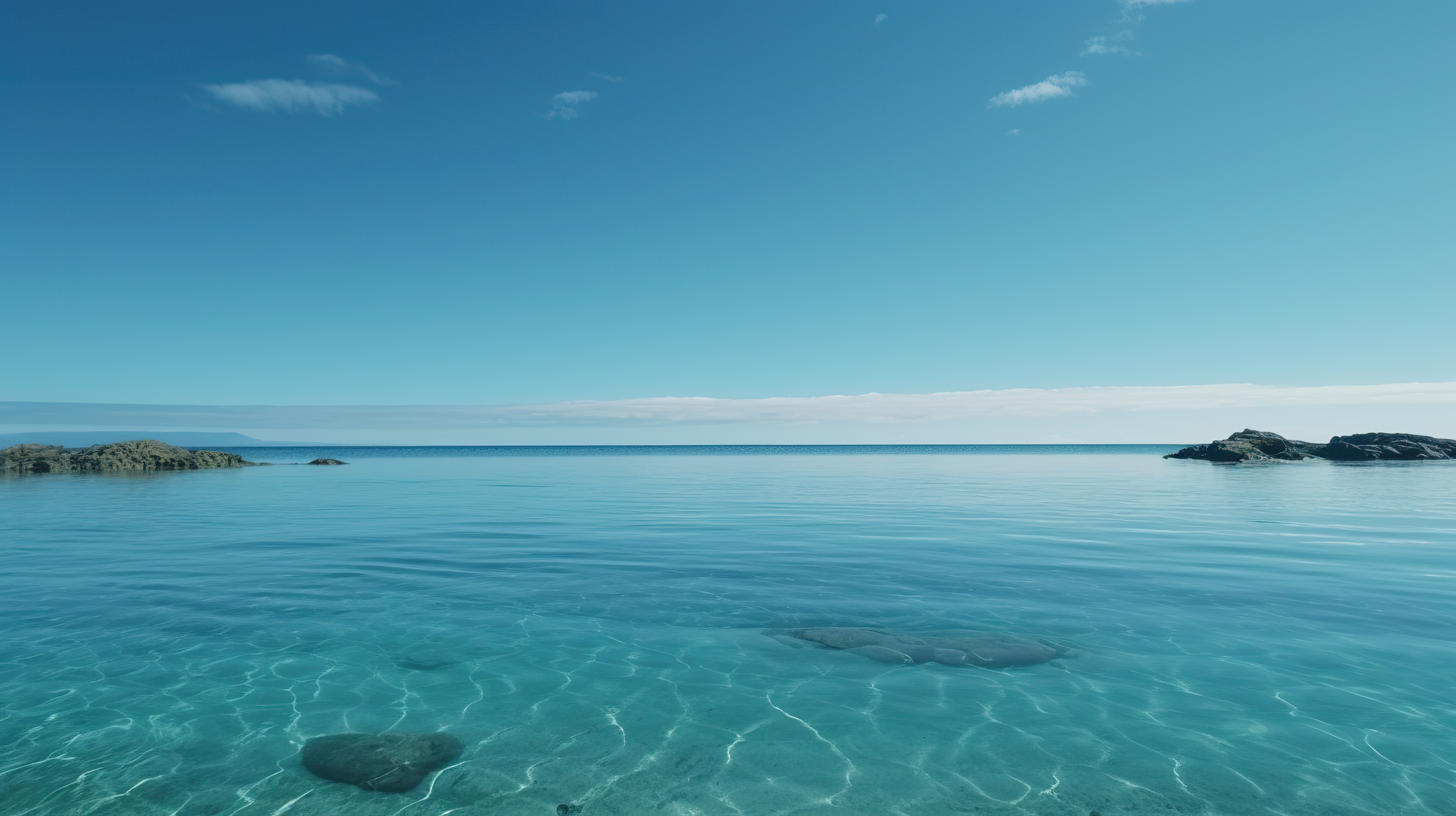 Beautiful blue sky and a beach with clear blue water and rocks on the shore