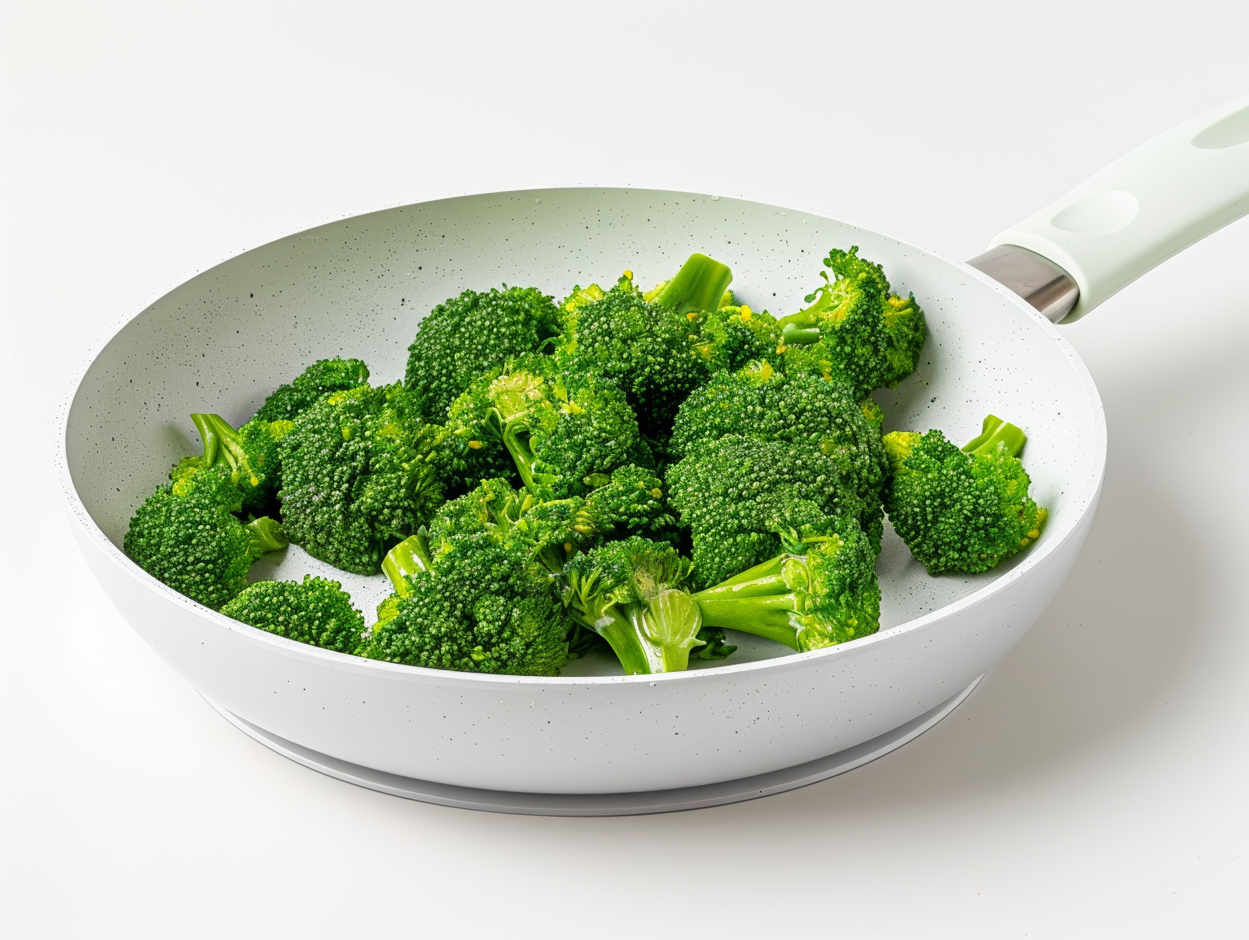 Broccoli florets in a frying pan close up isolated on white background