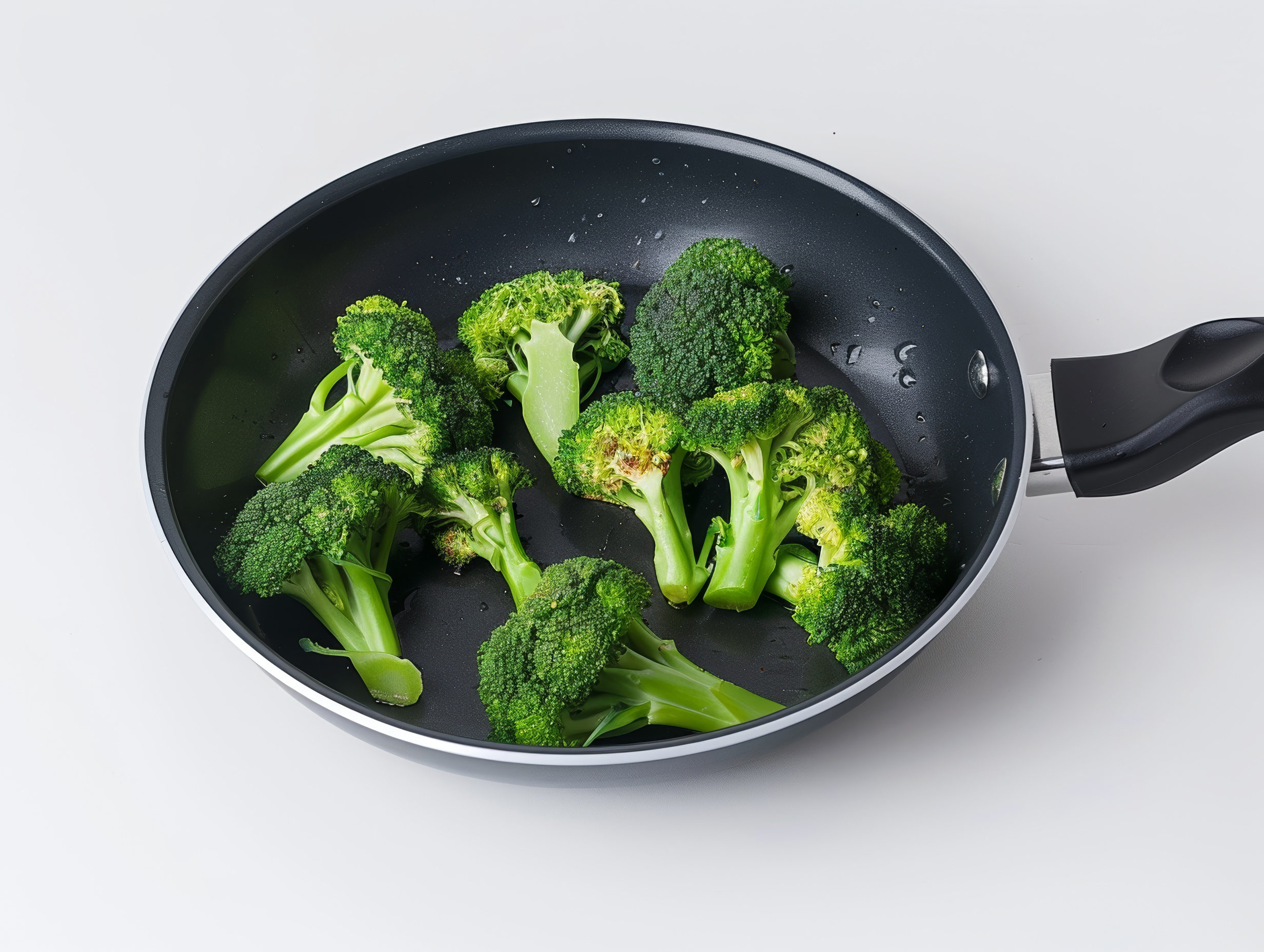 Broccoli florets in a frying pan close up isolated on white background