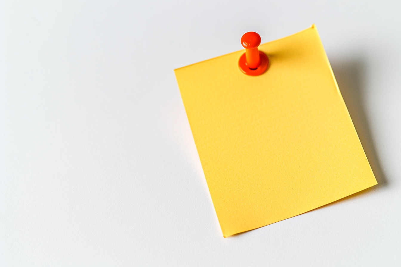 Yellow colored sticky note pinned on a white background