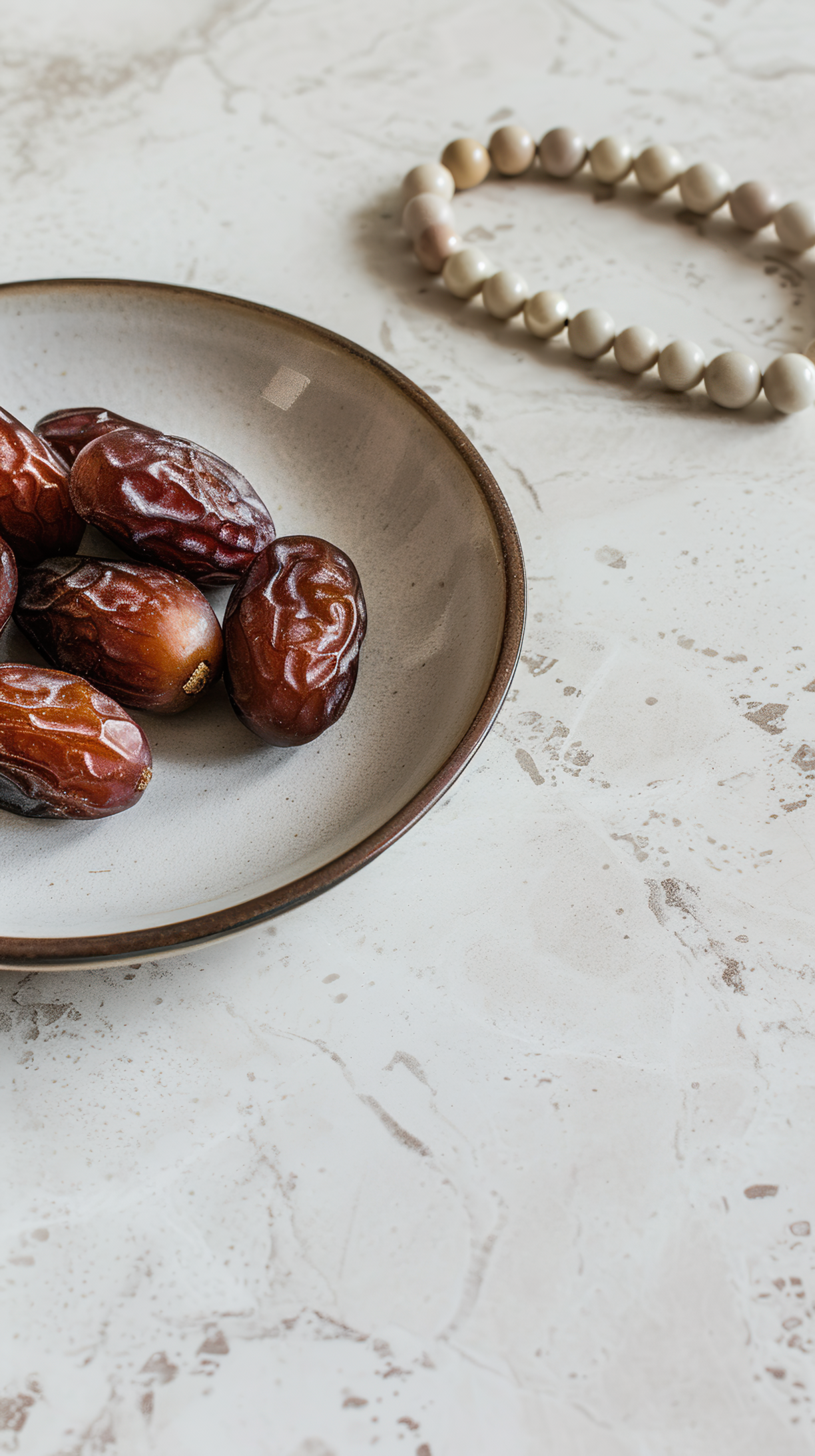 Plate with dates, decorative arabic lantern and rosary on a light background