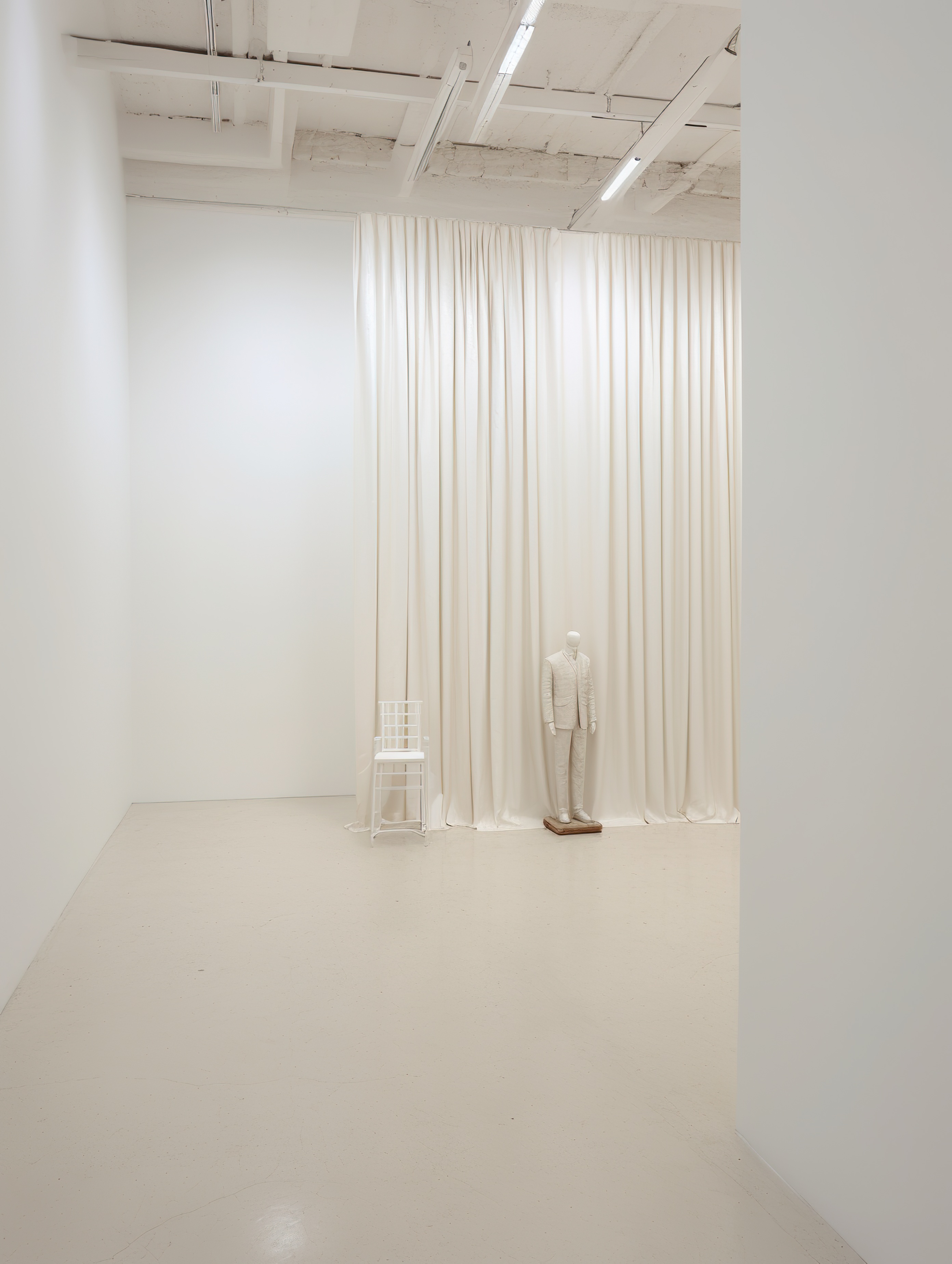 White room with a mannequin standing in the center and a white curtain hanging from the ceiling